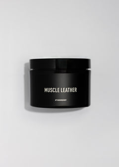 Black jar labeled Muscle Leather body scrub with a minimalist label