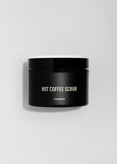 Black jar labeled Hot Coffee Scrub on a white backdrop