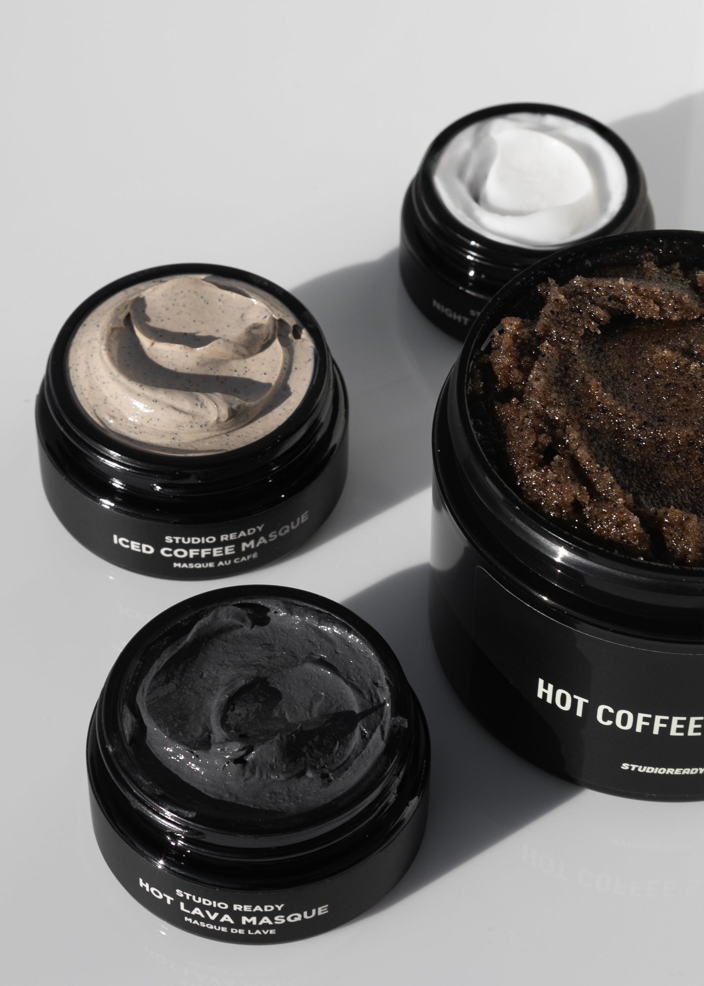 Ceremony four piece ritual skincare set with open jars of cream and scrub on a white surface