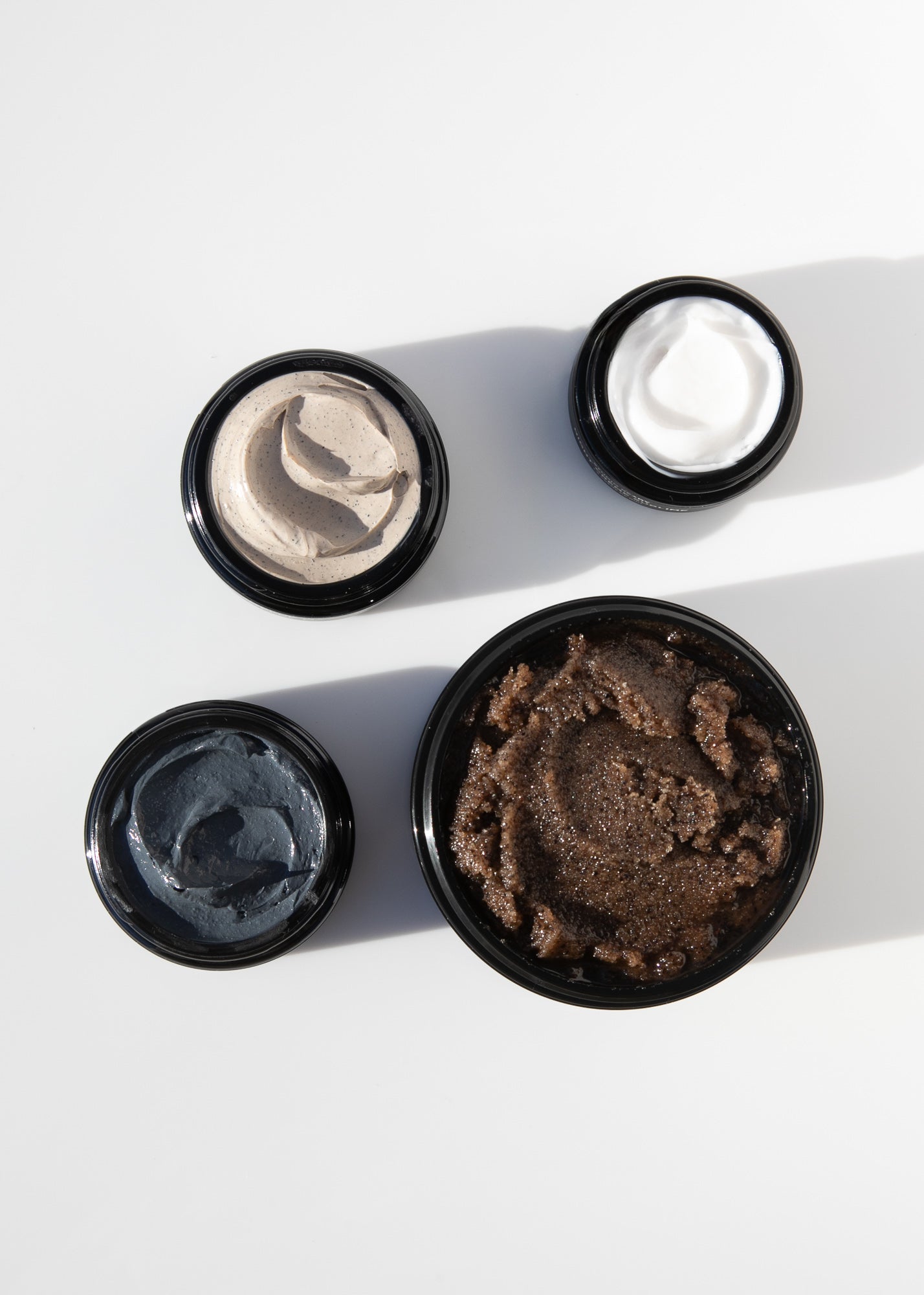 Ceremony four piece skincare ritual with cream and scrub jars arranged on white surface