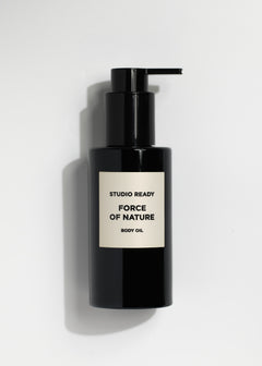 Black body oil bottle with pump on white background and beige label reading Force of Nature Body Oil.